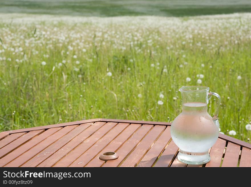 Jug wit cold water on table in the grassland