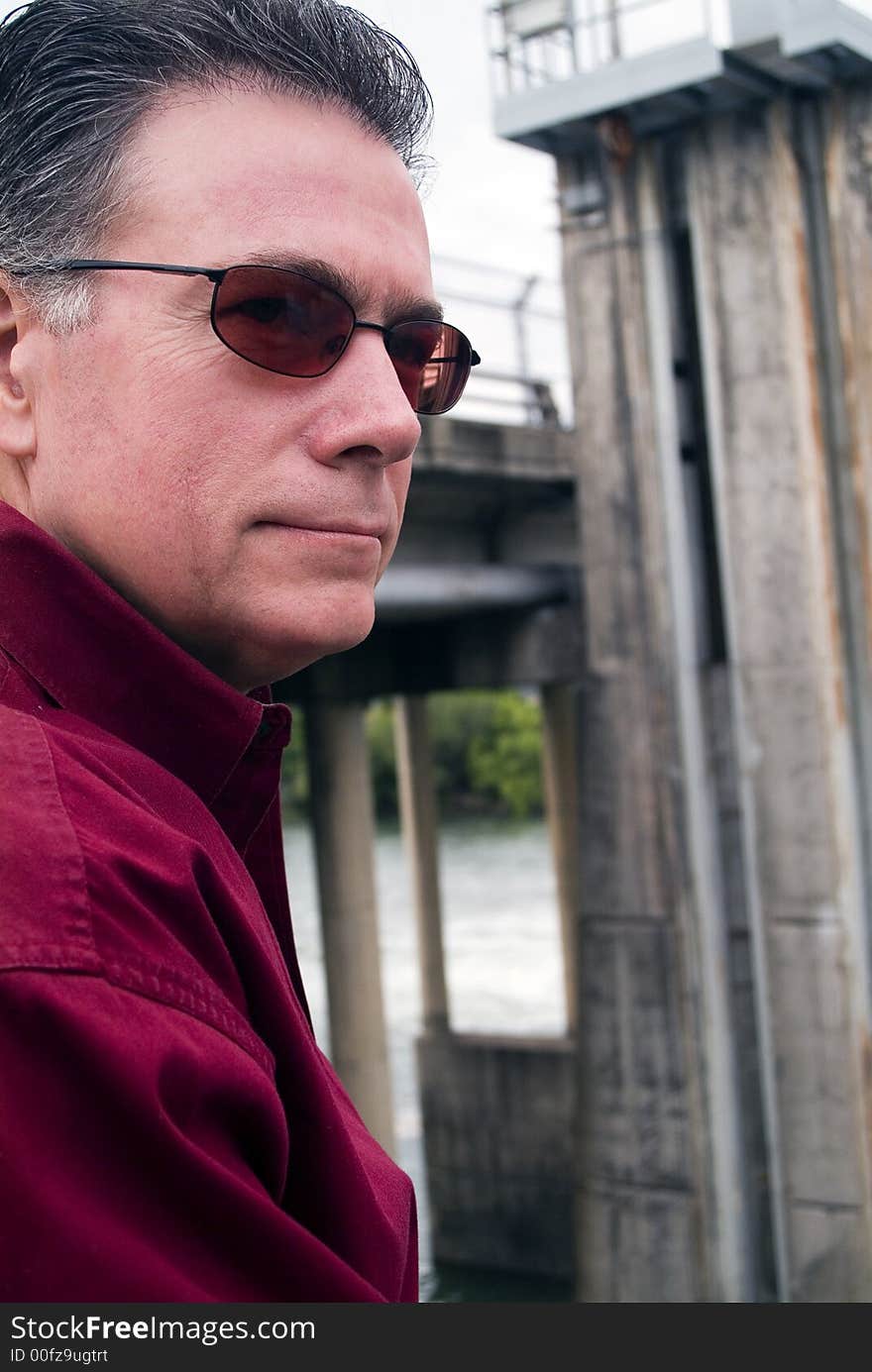 Man standing by a small dam with a peaceful, contemplative expression on his face. Man standing by a small dam with a peaceful, contemplative expression on his face.