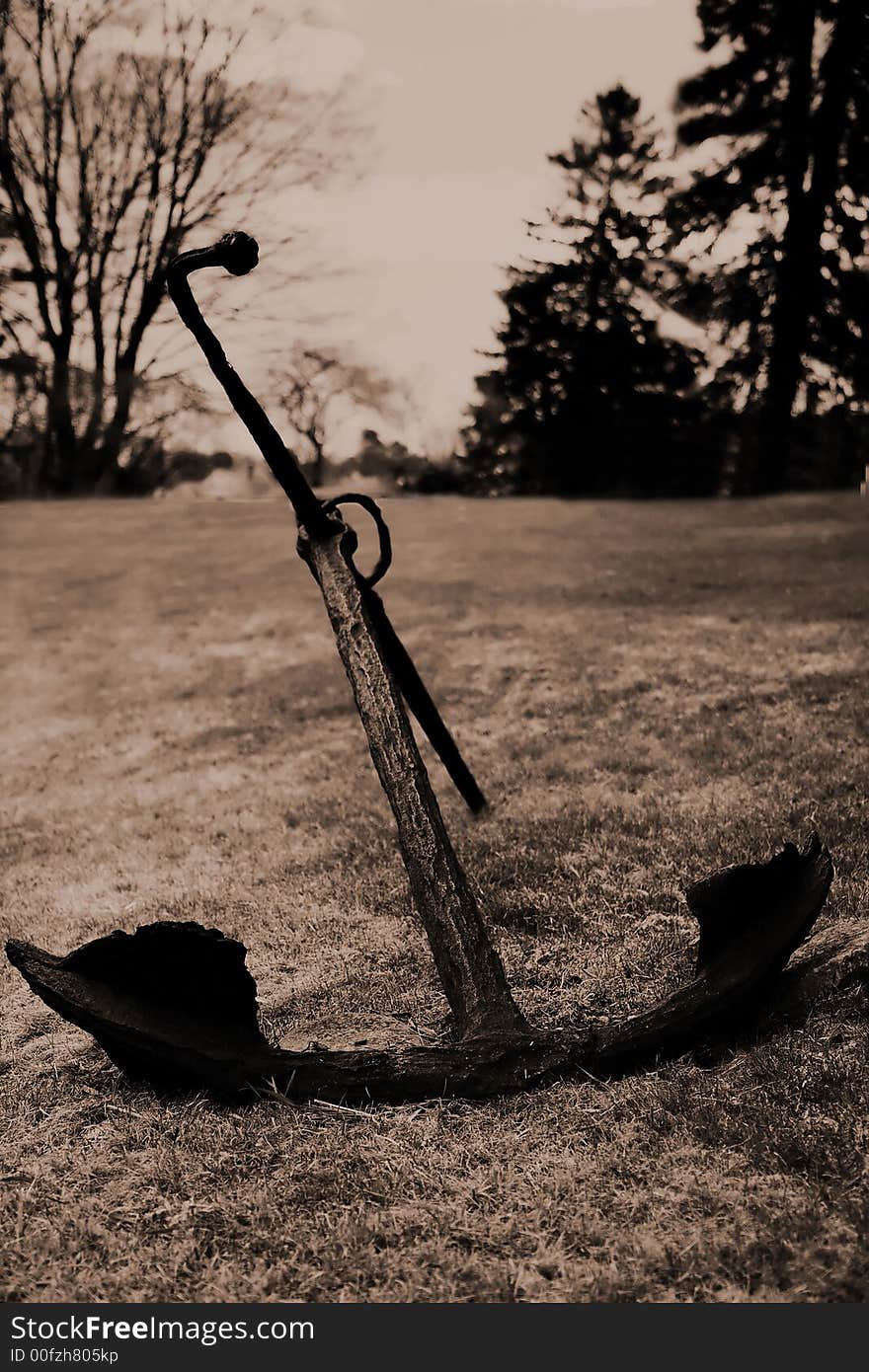 Old abandoned anchor stuck on the ground. Sepia tone. Old abandoned anchor stuck on the ground. Sepia tone.