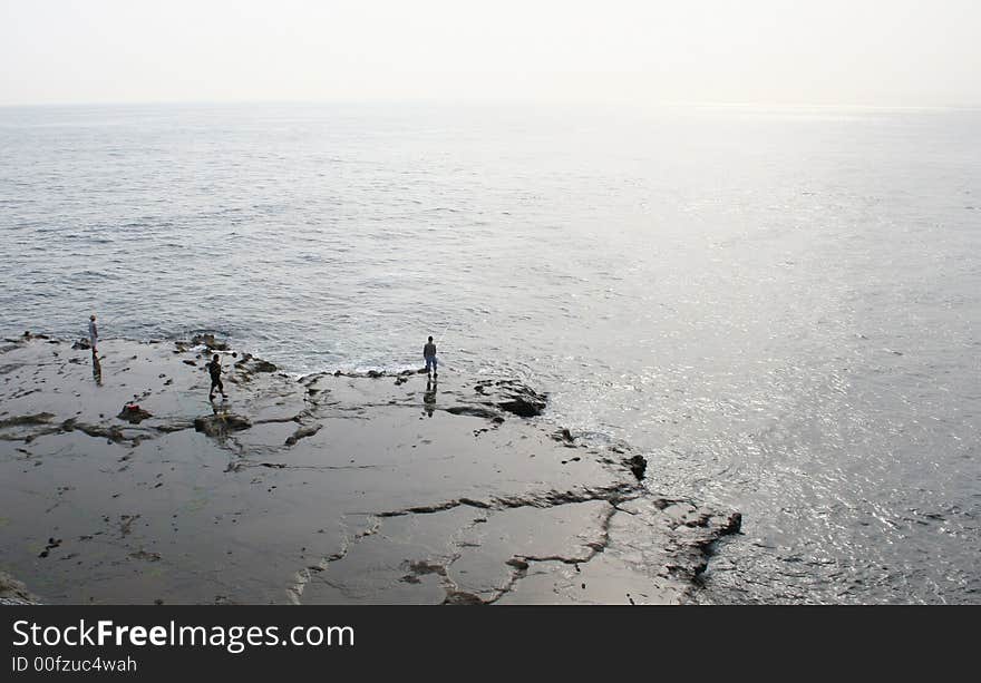 Some people fishing by the sea.