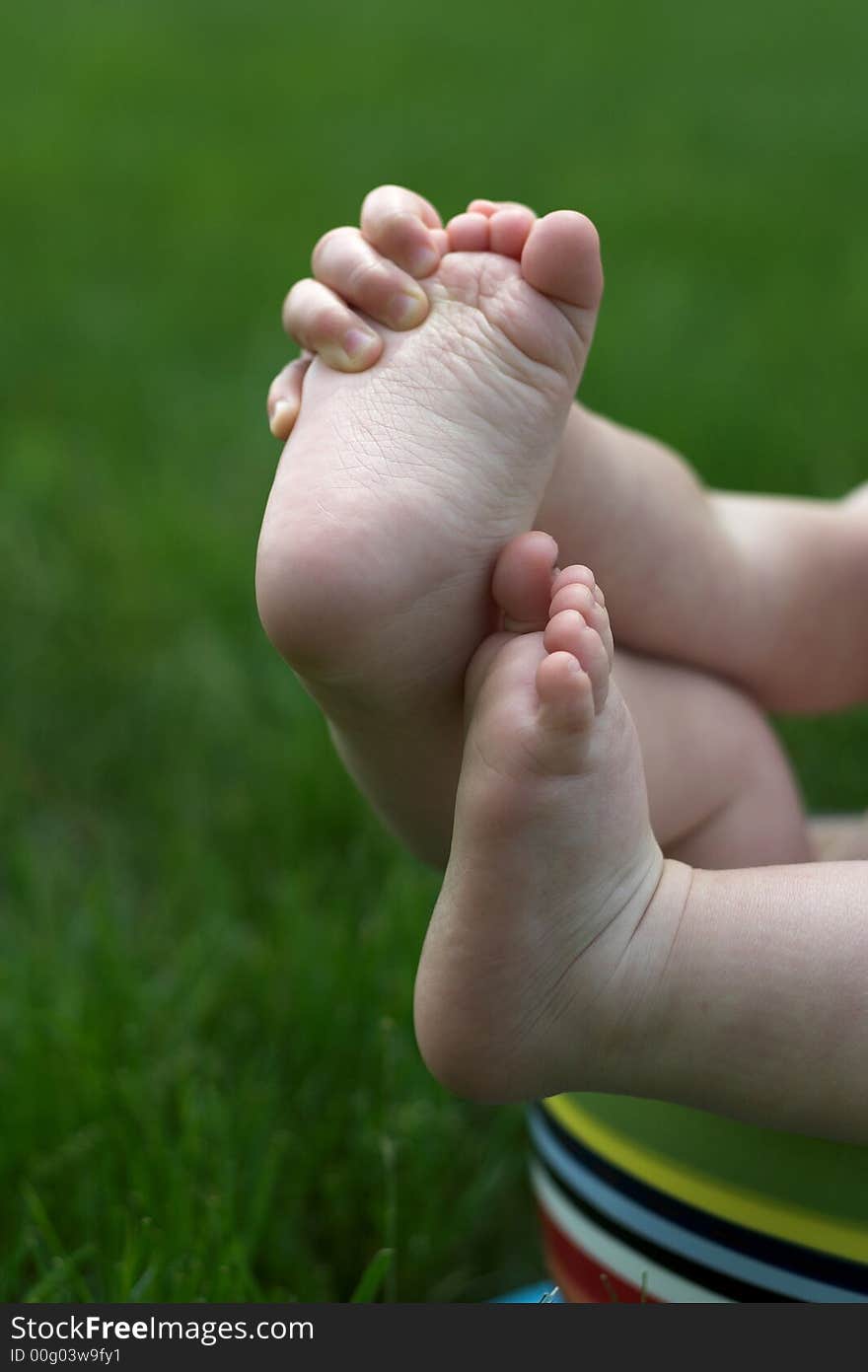 Image of a baby's feet peeking out over the side of a colorful cup. Image of a baby's feet peeking out over the side of a colorful cup