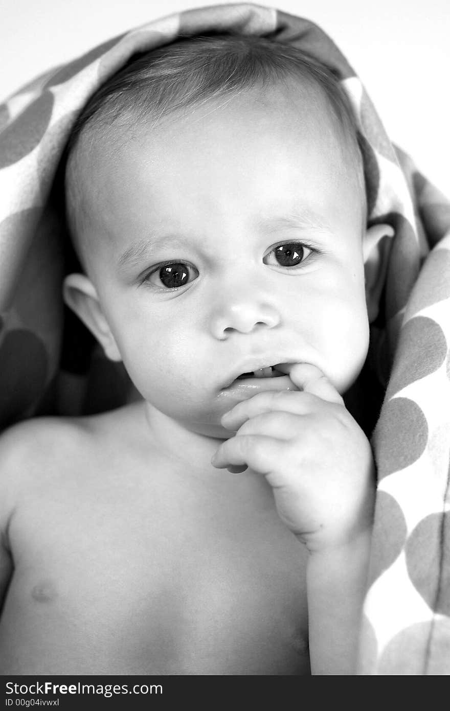 Black and white image of a cute toddler peeking out from under a blanket. Black and white image of a cute toddler peeking out from under a blanket