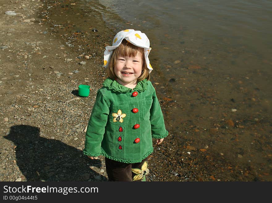 Small girl in green plays ashore rivers. Small girl in green plays ashore rivers