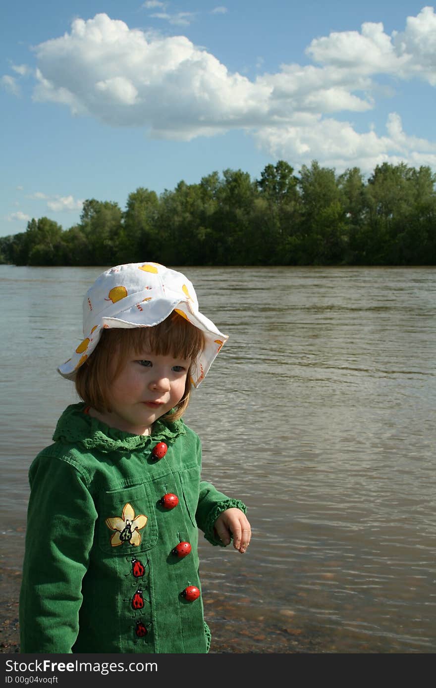 Small girl in green plays ashore rivers. Small girl in green plays ashore rivers