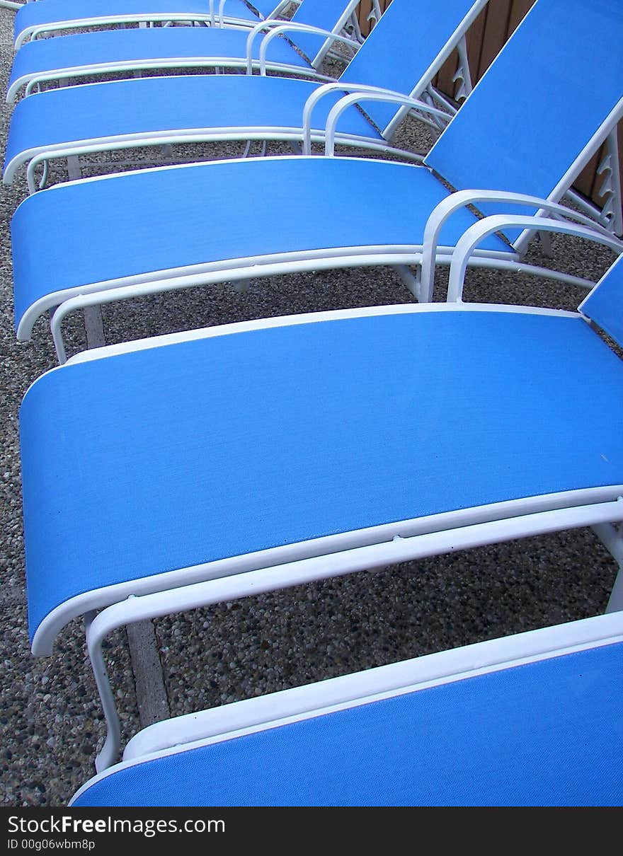 Empty pool lounge chairs neatly placed in a row. Empty pool lounge chairs neatly placed in a row