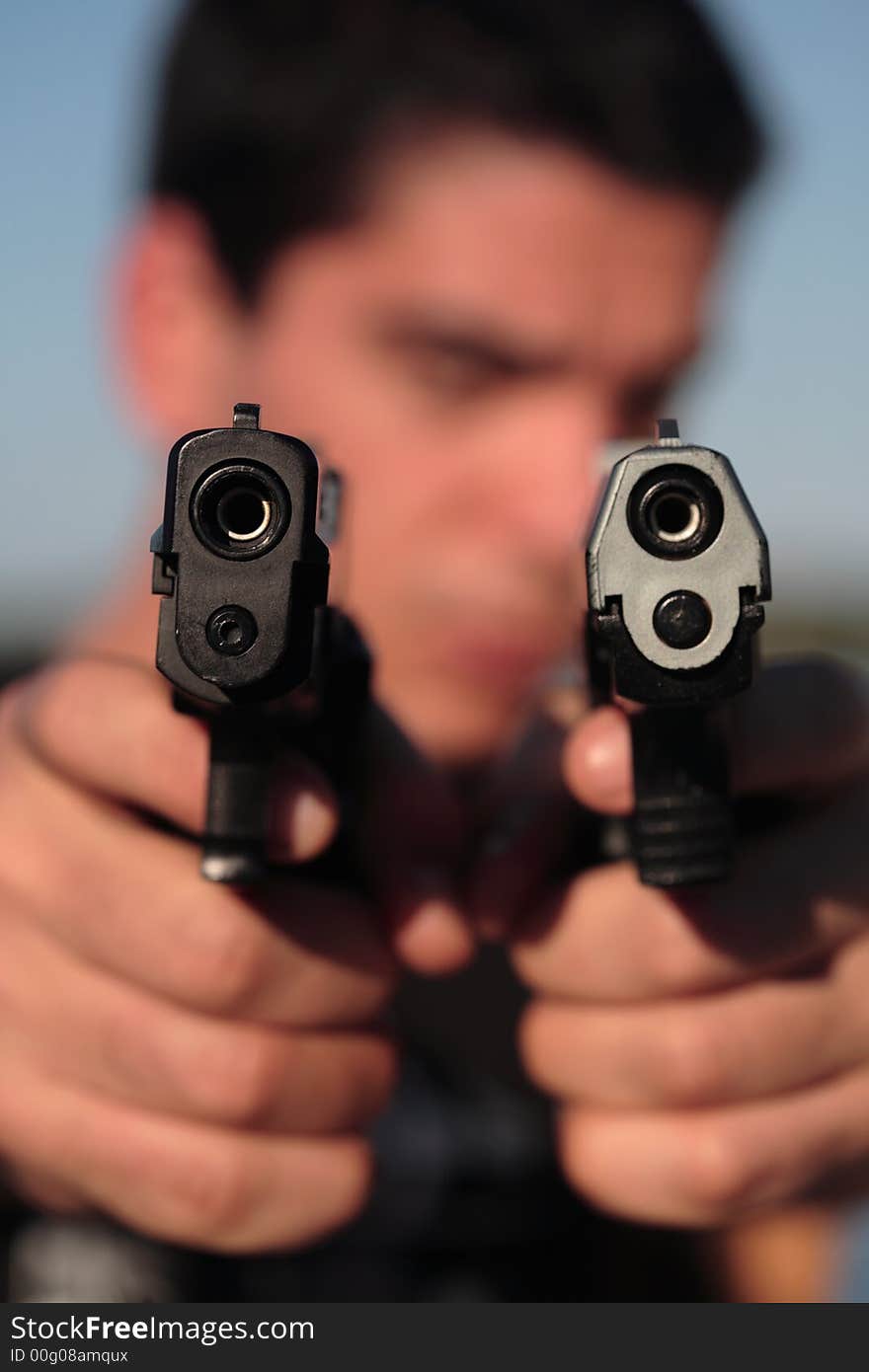 A man holding a pistol and pointing it at the camera. (This image is part of a series). A man holding a pistol and pointing it at the camera. (This image is part of a series).