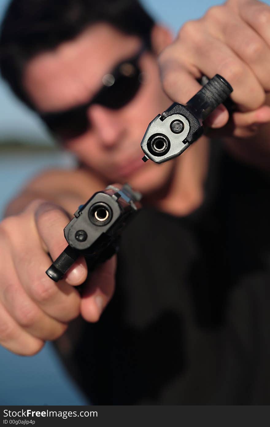 A man holding a pistol and pointing it at the camera. (This image is part of a series). A man holding a pistol and pointing it at the camera. (This image is part of a series).