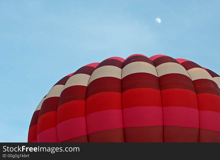 Hot air balloon ascending during evening with moon shining above. Hot air balloon ascending during evening with moon shining above