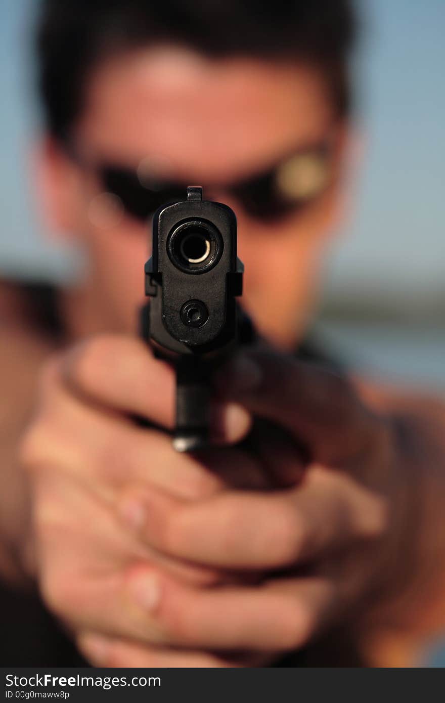 A man holding a pistol and pointing it at the camera. (This image is part of a series). A man holding a pistol and pointing it at the camera. (This image is part of a series).