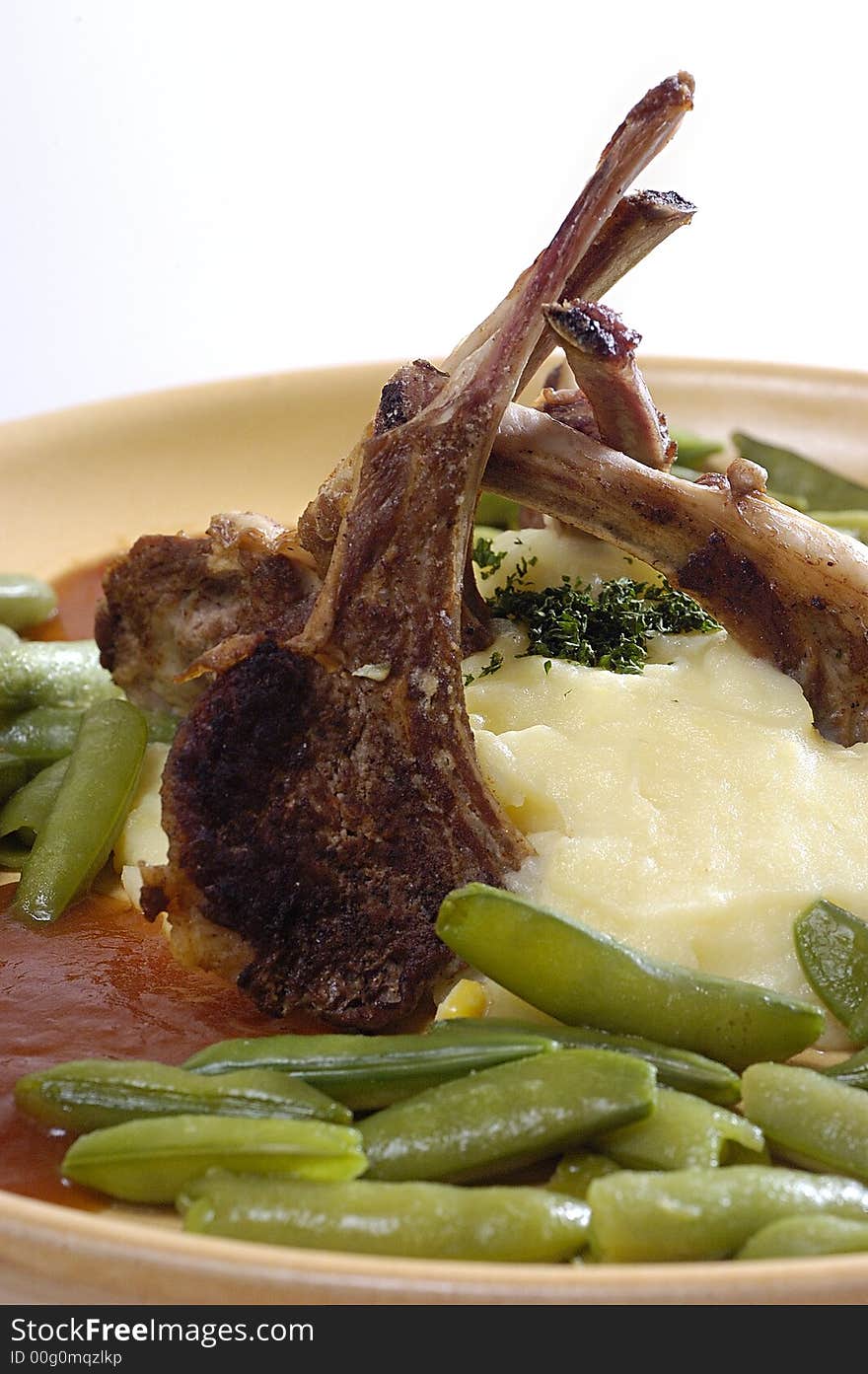 Picture of pork ribs with sauce, stewed vegetables and mashed potatoes.