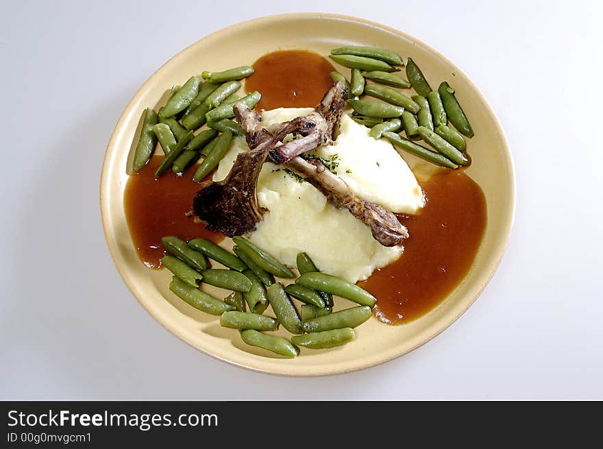 Picture of pork ribs with sauce, stewed vegetables and mashed potatoes.