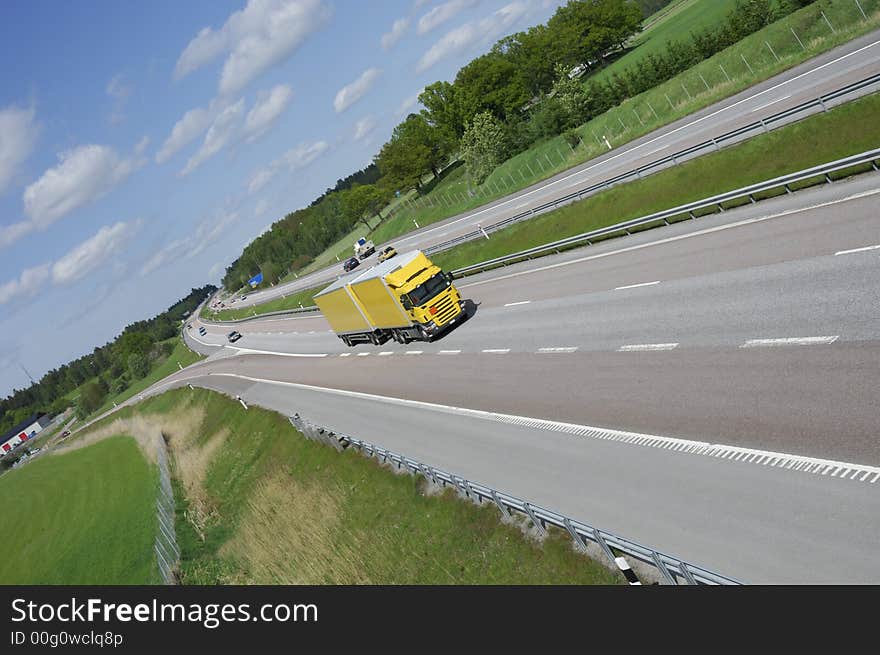 Large yellow truck speeding on highway set in a country-side surrounding, no trademarks. Large yellow truck speeding on highway set in a country-side surrounding, no trademarks