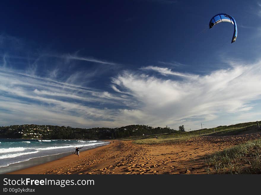 Lonely kiteboarder walking on the beach.