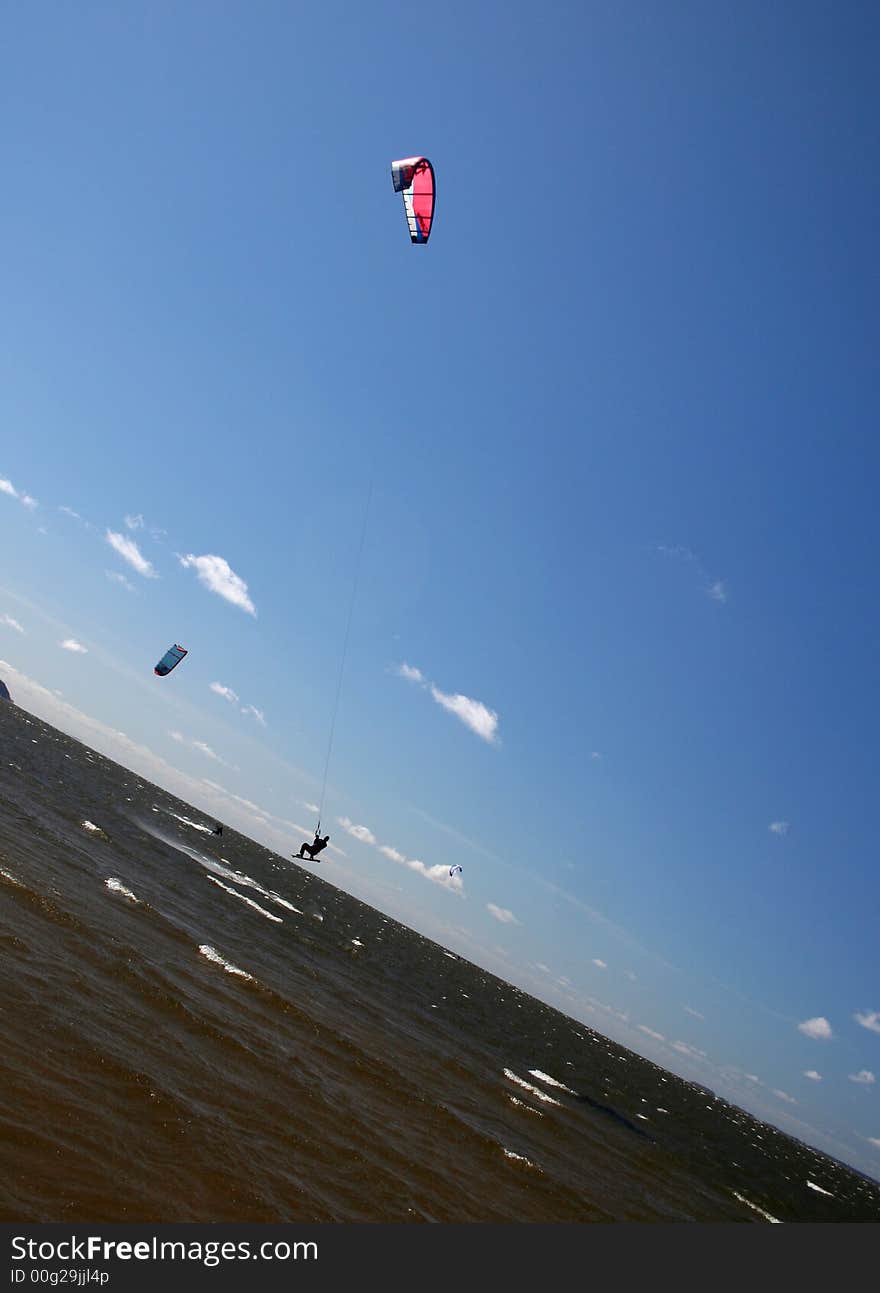 Bold kitesurfer is jumping in the blue sky. Bold kitesurfer is jumping in the blue sky