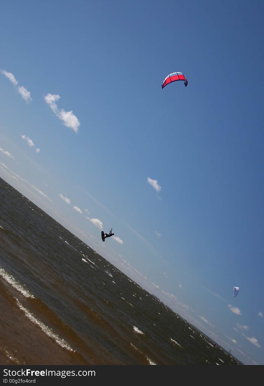 Bold kitesurfer is jumping in the blue sky. Bold kitesurfer is jumping in the blue sky