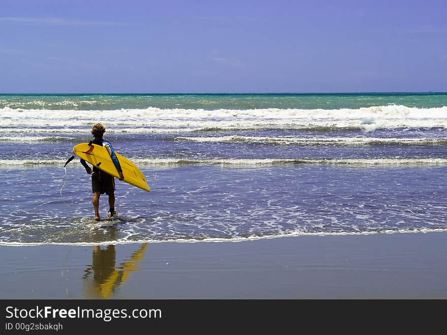 A surfer  enter into the rough sea, ready to surf. A surfer  enter into the rough sea, ready to surf.