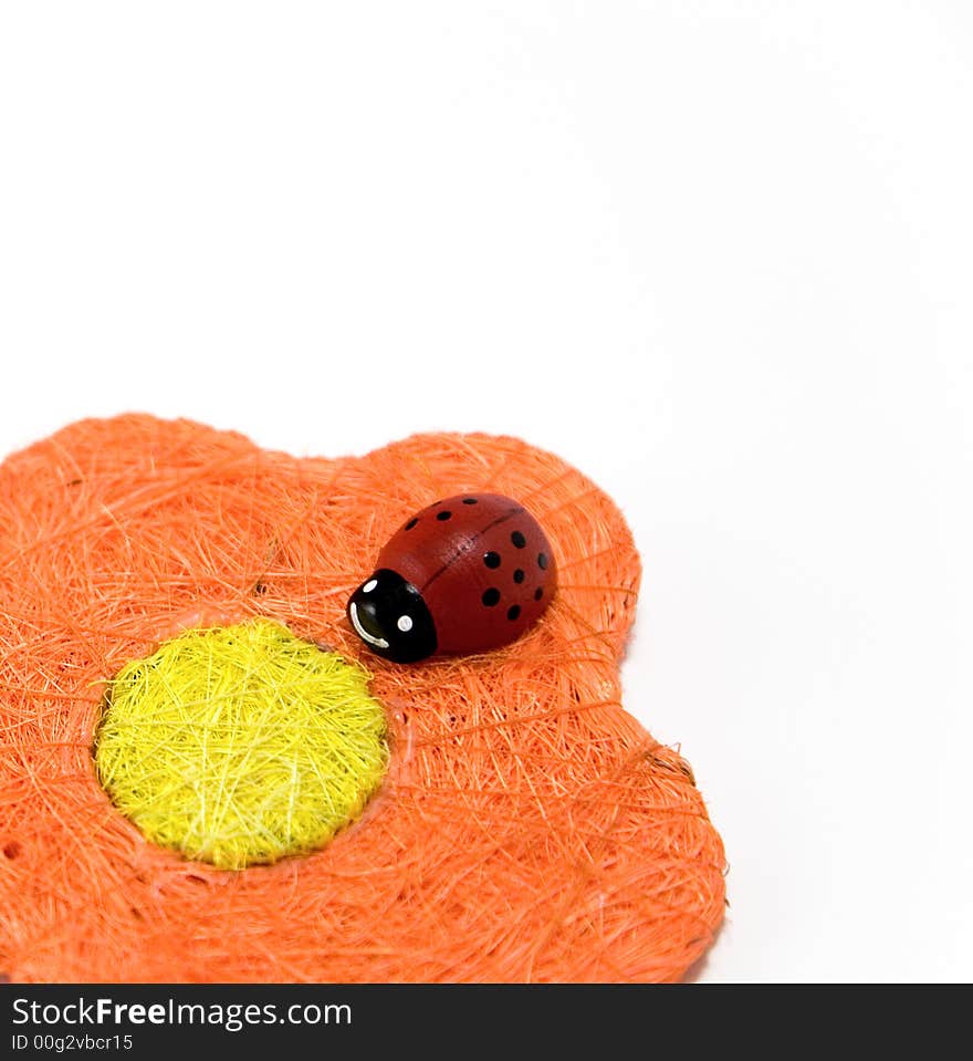 Red wooden ladybird on an orange artificial flower. Red wooden ladybird on an orange artificial flower