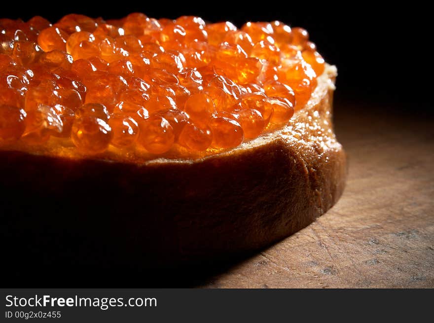 Sandwich with red caviar on a wooden table