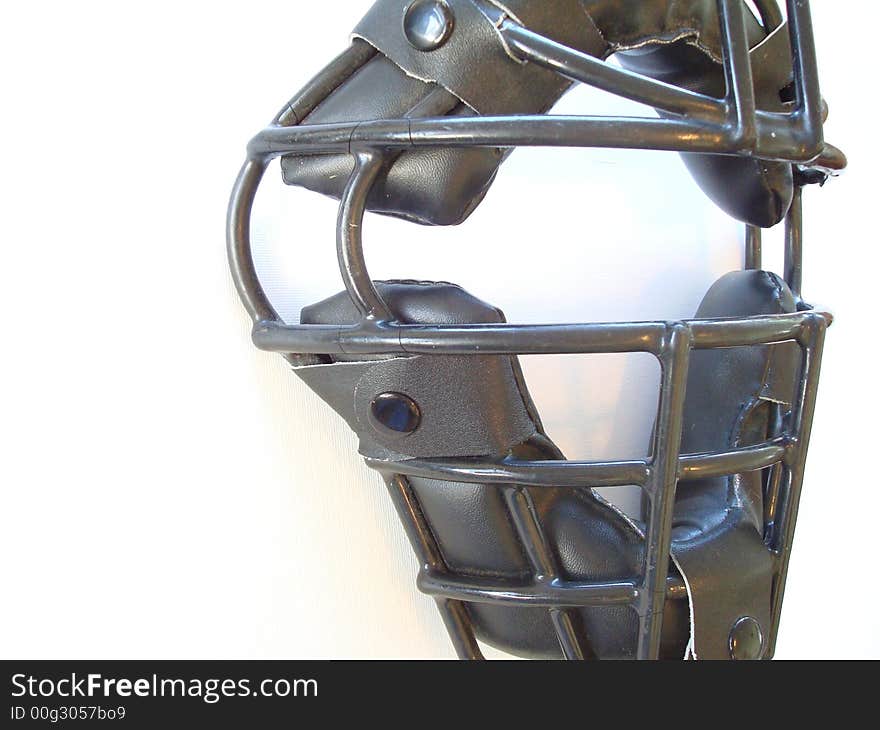 Black baseball catcher’s face mask on a white background with space for ad copy / text. Black baseball catcher’s face mask on a white background with space for ad copy / text.