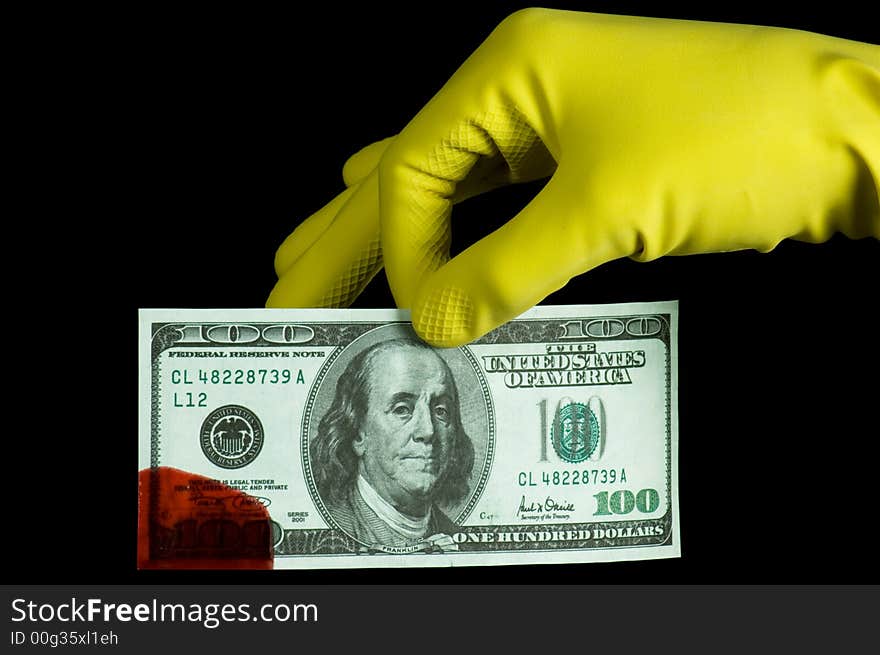 A hand in glove holding bloody dollar banknote