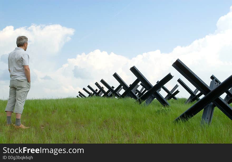 The veteran of war stands in a field near anti-tank strengthenings. The veteran of war stands in a field near anti-tank strengthenings