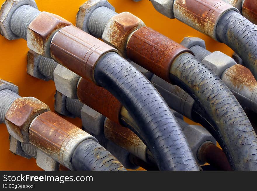 Image shows a set of old and weathered tubes connected to a metallic surface. Image shows a set of old and weathered tubes connected to a metallic surface