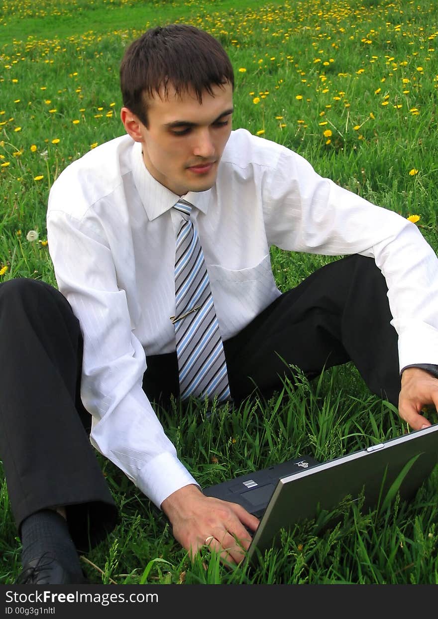 Businessman with laptop sitting on the grass