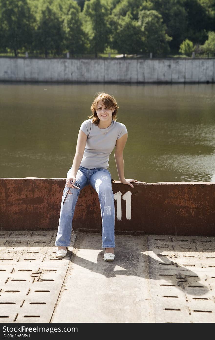 Pretty girl sitting on the riverbank. Pretty girl sitting on the riverbank