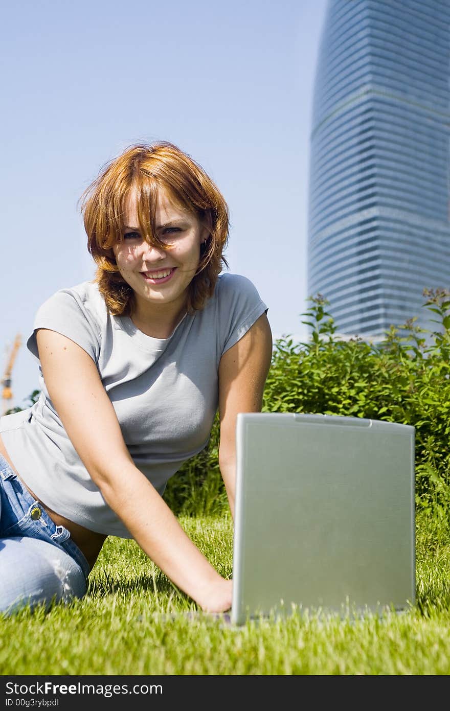 Young girl with laptop on the grass before office building. Young girl with laptop on the grass before office building