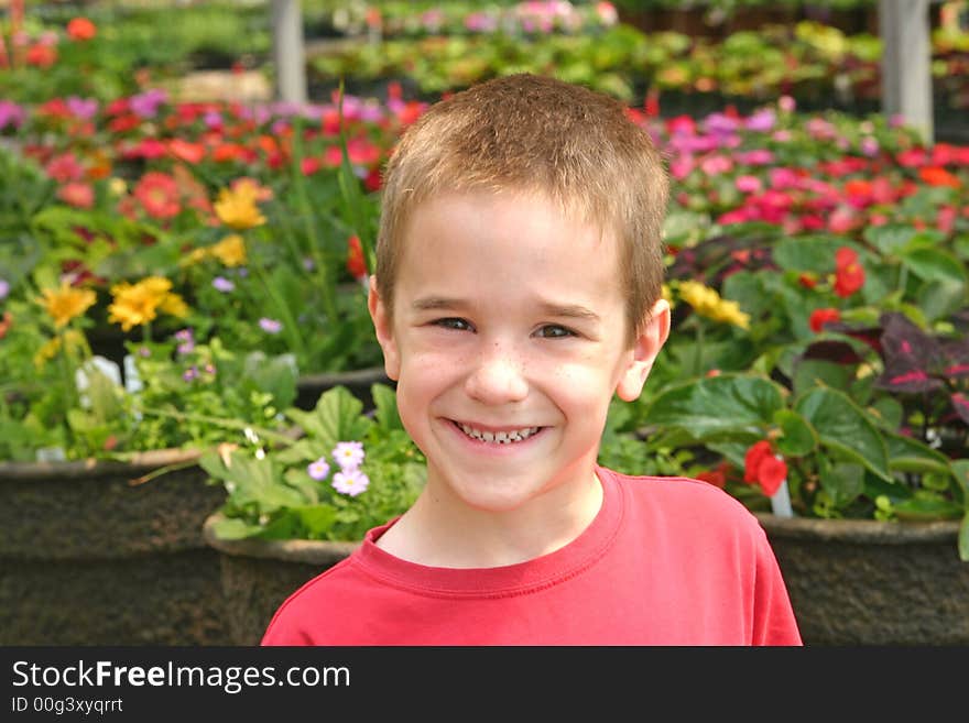 Young Boy Smiling in Front of Flowers