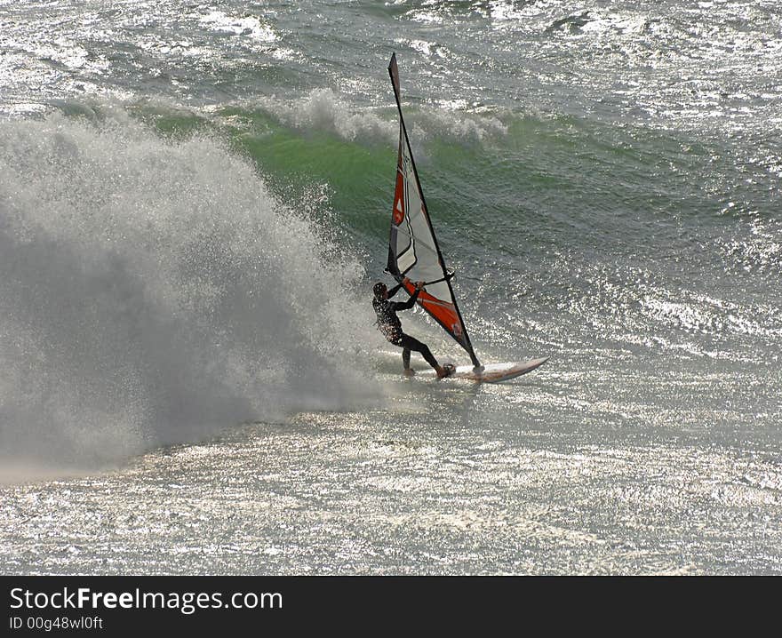 Fast moving windsurfer surfing over large waves