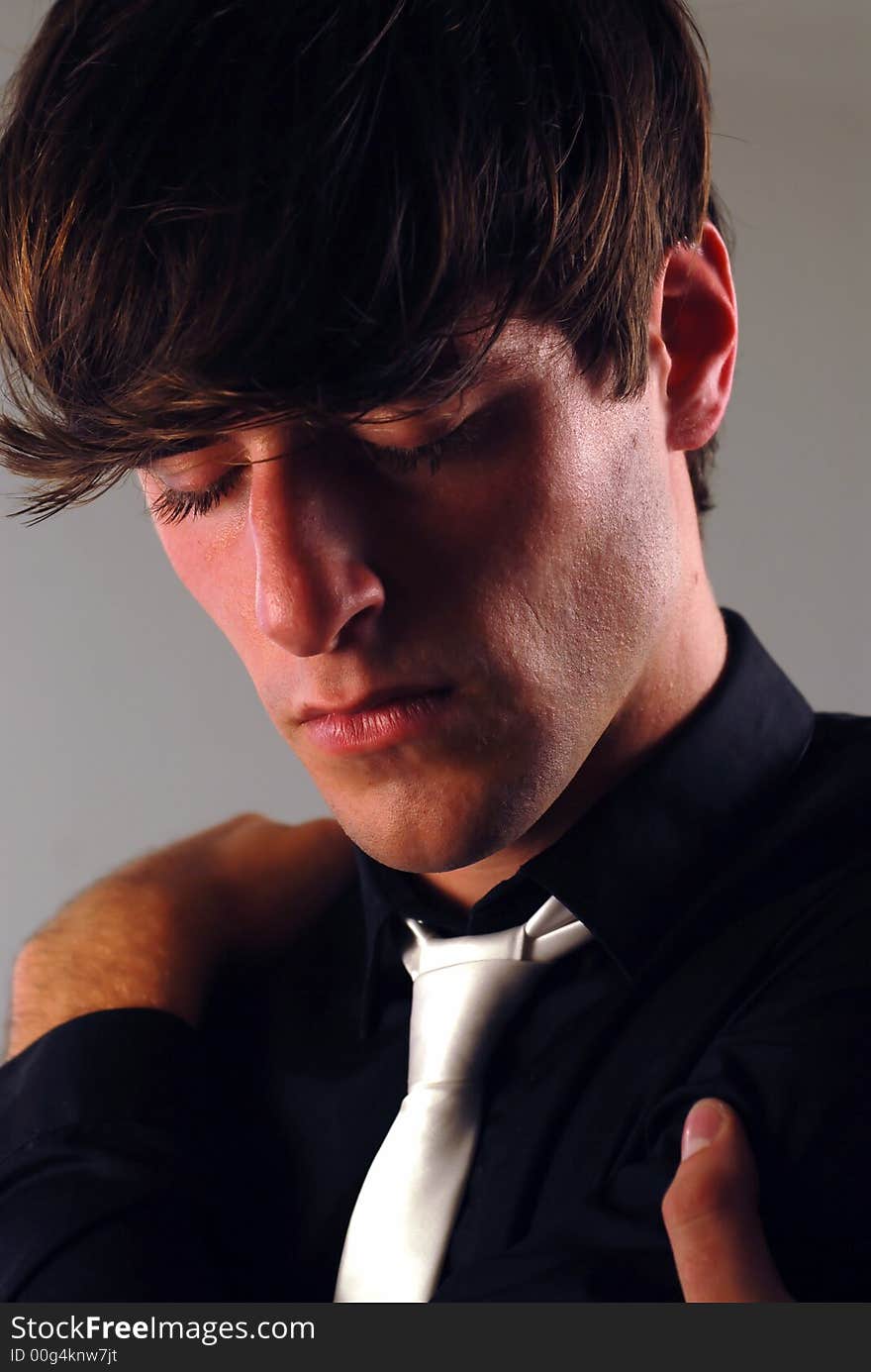 Portrait of a young man with a black shirt and a white tie in a thoughtful pose. Portrait of a young man with a black shirt and a white tie in a thoughtful pose.