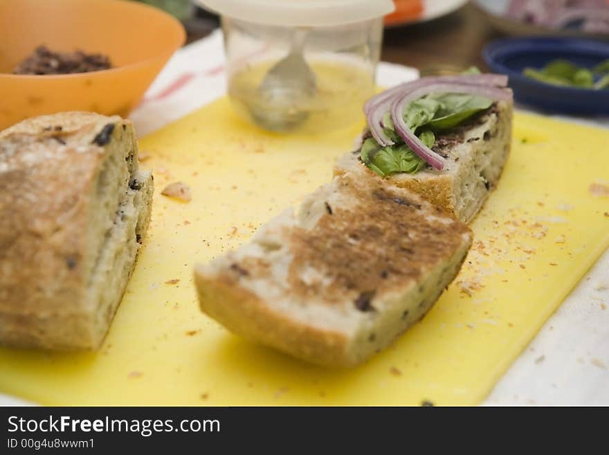 Preparing vegatarian sandwiches with letuce, bell peppers, and  tomotoes at home. Sandwich on cutting board with ingredients. Preparing vegatarian sandwiches with letuce, bell peppers, and  tomotoes at home. Sandwich on cutting board with ingredients.