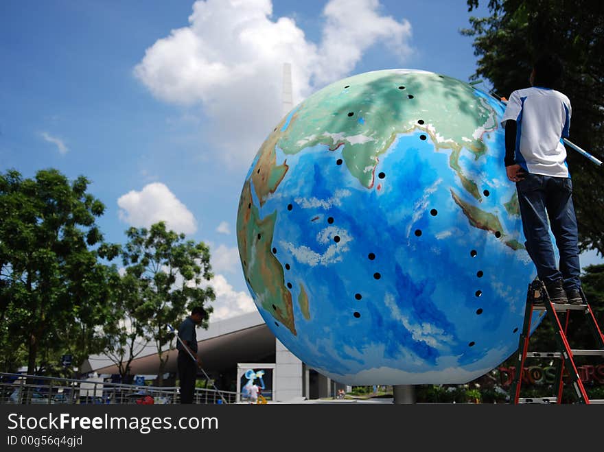 Worker painting the globe in the parks