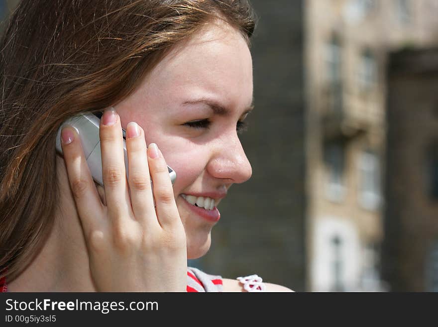 Young smiling girl with cell phone, building in the background is out of focus