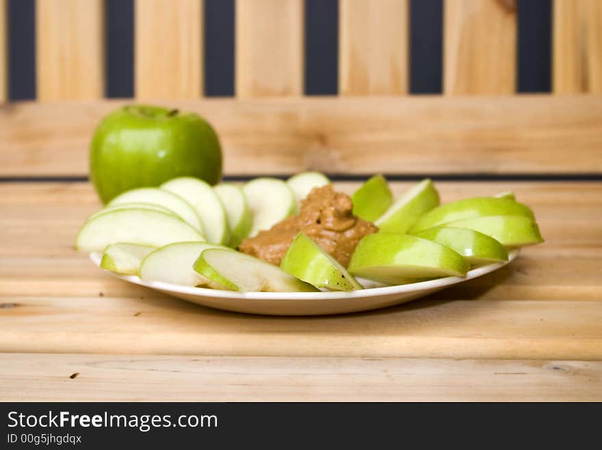 A plate of tasty granny smith apples and peanutbutter. A plate of tasty granny smith apples and peanutbutter