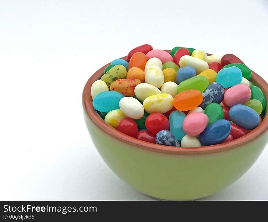 Assortment of colorful jelly beans in a mini green bowl on a white background. Assortment of colorful jelly beans in a mini green bowl on a white background.