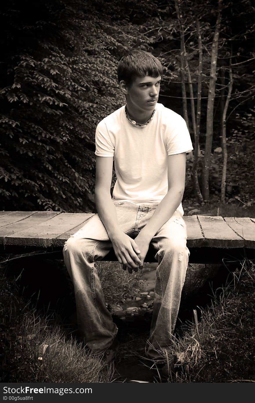 A handsome young man sitting on a bridge, black and white. A handsome young man sitting on a bridge, black and white