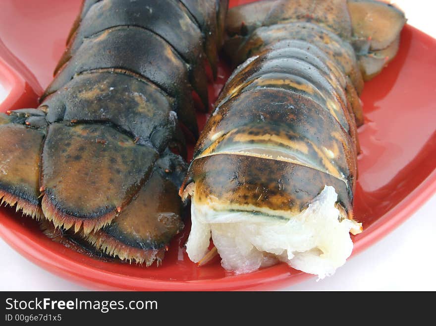 Two lobsters presented on a red plate close up. Two lobsters presented on a red plate close up