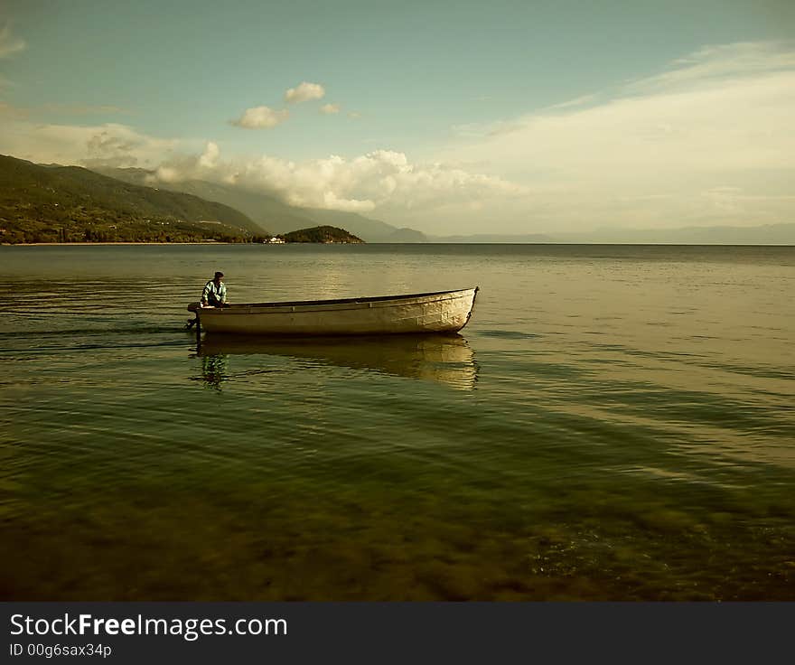 Lonely ferryman on boat in mountain lake