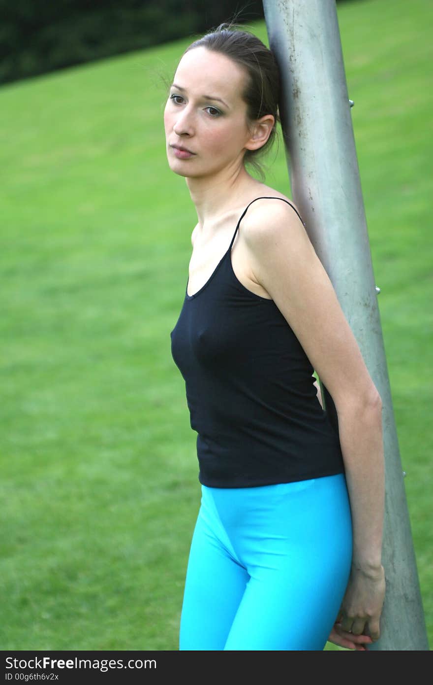 sad woman leaning against the metal pipe and having rest after workout