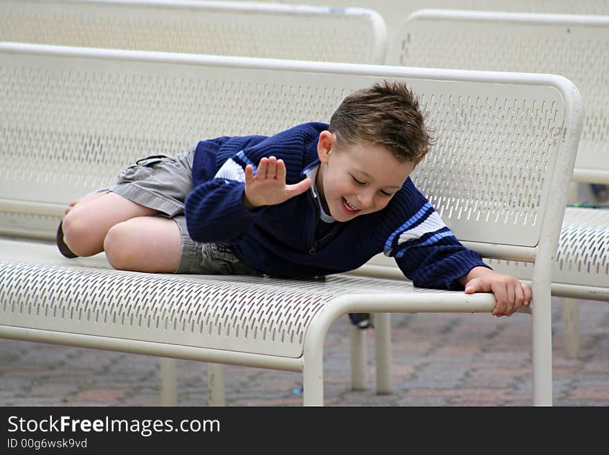 Boy laughing at joke on bench of park. Boy laughing at joke on bench of park.