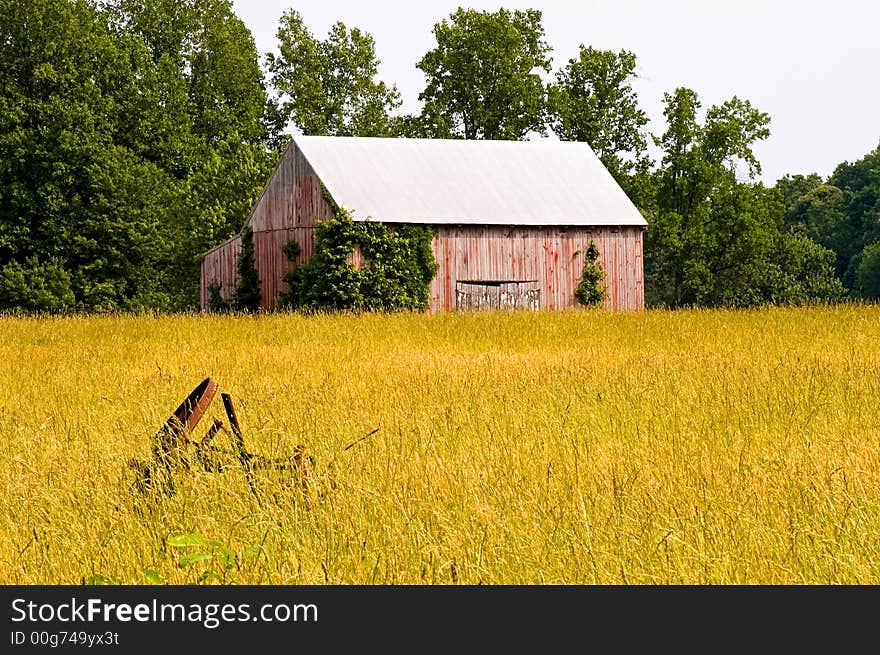 A view of an old dilapidated red barn seen across a hayfield in southern Maryland, once used to store and dry tobacco leaves. A view of an old dilapidated red barn seen across a hayfield in southern Maryland, once used to store and dry tobacco leaves.