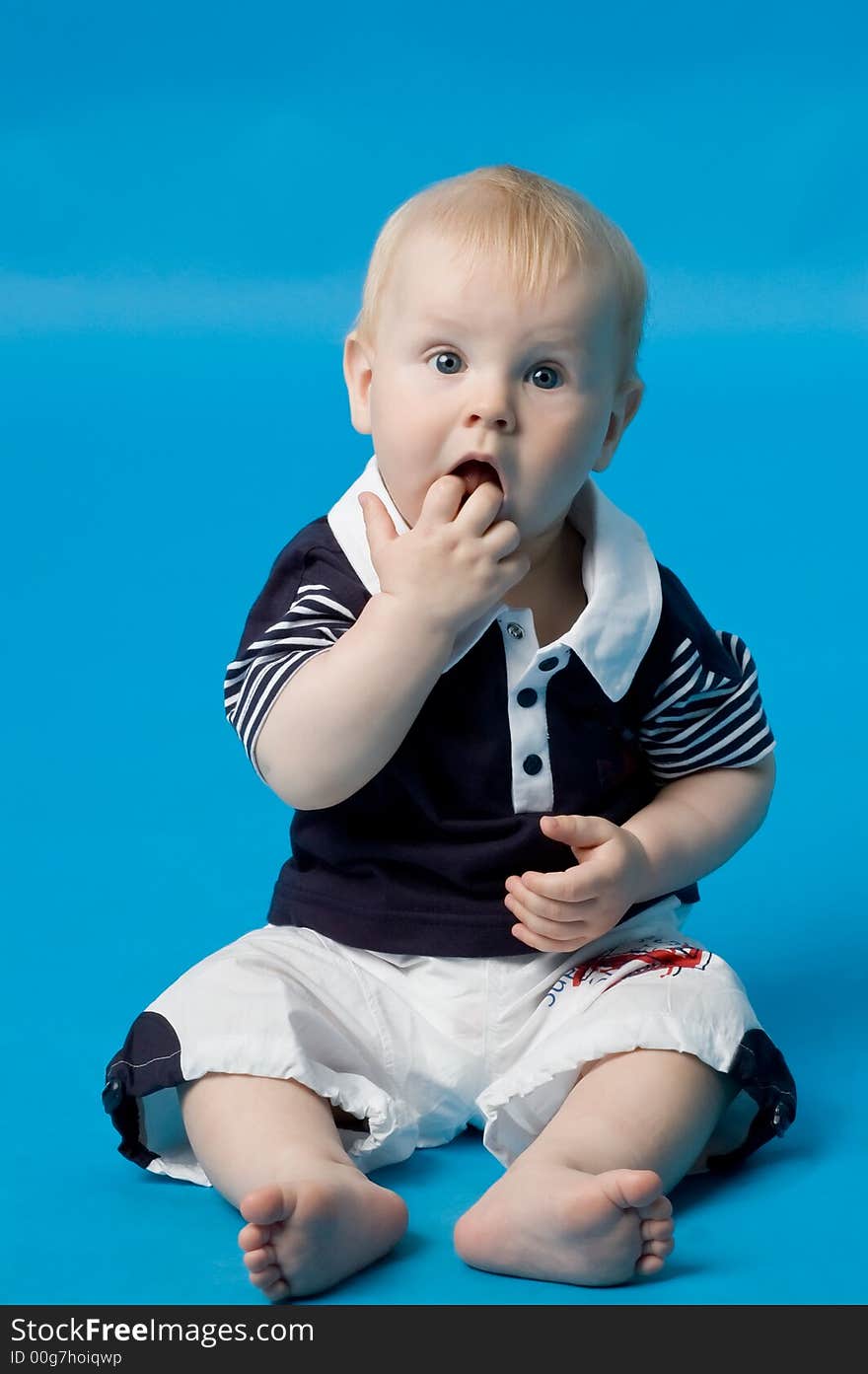 The small smiling child in studio, on a blue background. The small smiling child in studio, on a blue background