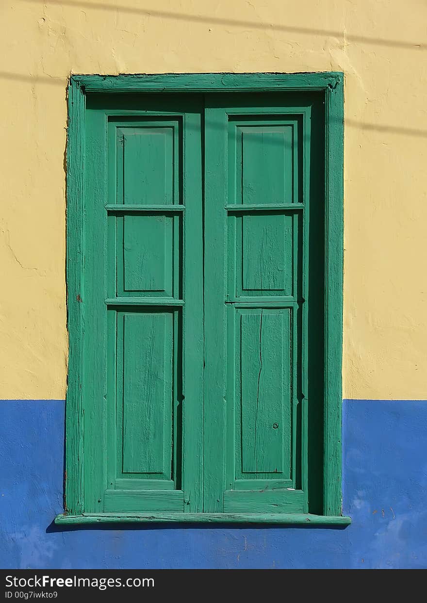 Green window with wooden blend case in colored facade on La Gomera Island