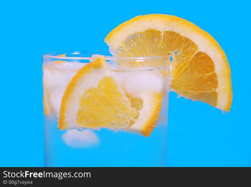 Bright juicy oranges in a glass on a blue background. Bright juicy oranges in a glass on a blue background