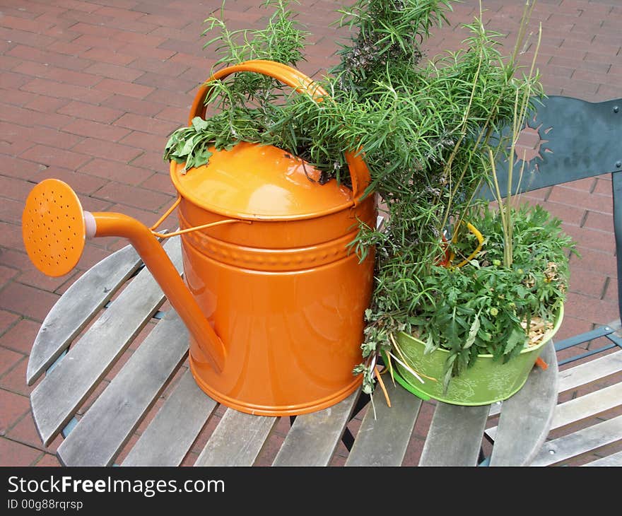 Orange watering can standing on table. Orange watering can standing on table.