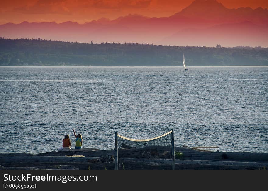 Two girls at the beach in Edmonds, WA with a sailboat and volley ball net. Two girls at the beach in Edmonds, WA with a sailboat and volley ball net