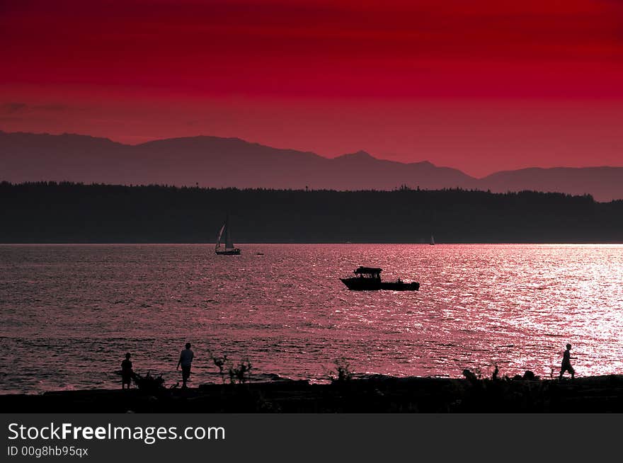 People play on the beach while the sun sets on the olympic Mountains near Seattle, WA. People play on the beach while the sun sets on the olympic Mountains near Seattle, WA