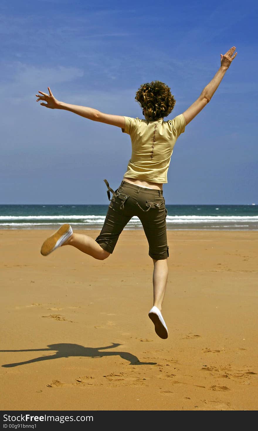 A photo of a happy girl jumping in the beach.